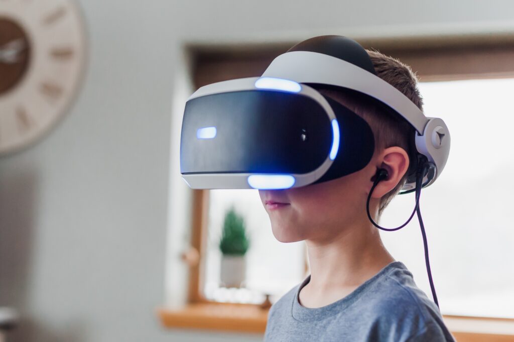 A small child wears a virtual reality headset. His face is completely obscured behind it.